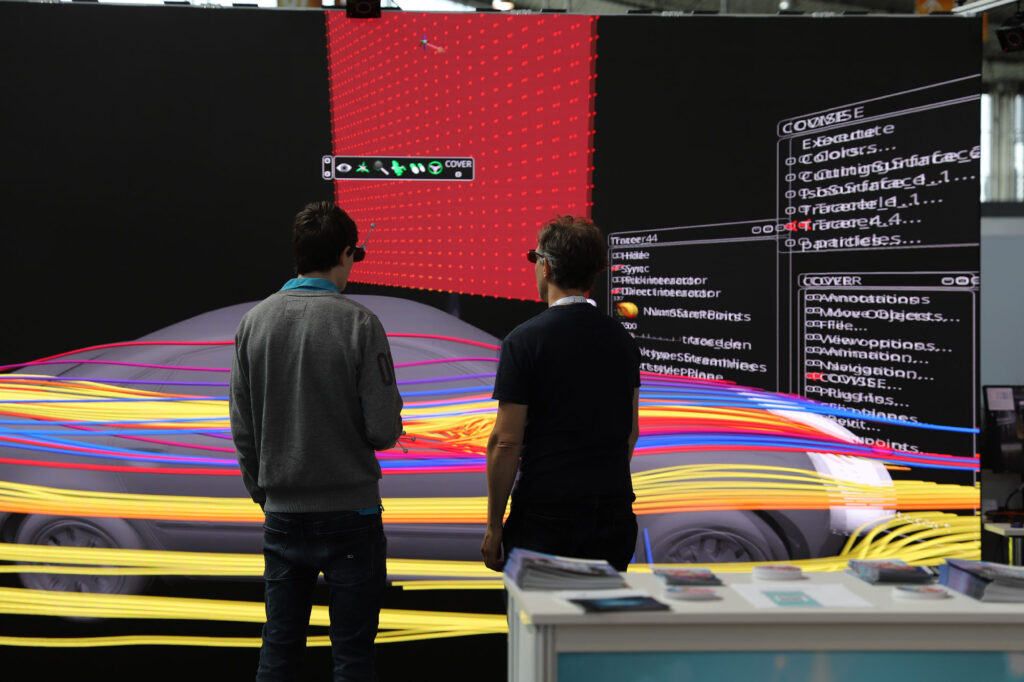 Photo of the booth, showing two persons in front of a visualisation of a car.